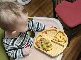 A baby in a high chair wearing an upcycled shirt