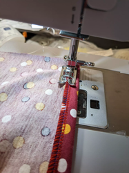 A sewing machine sewing the folded hem