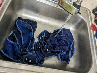 Blue diapers in the sink under a stream of water